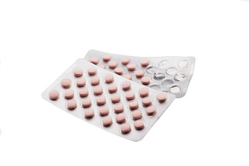 Old medicinal pink pills with expired shelf life on a white background. Isolated