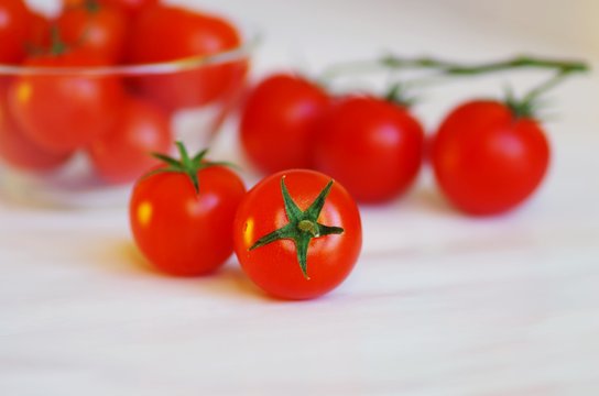 Fresh organic tomato cherry in a glass bowl and on a white background. Picture design for food backgrounds, detox snacks, weight loss and eating healthy concept.