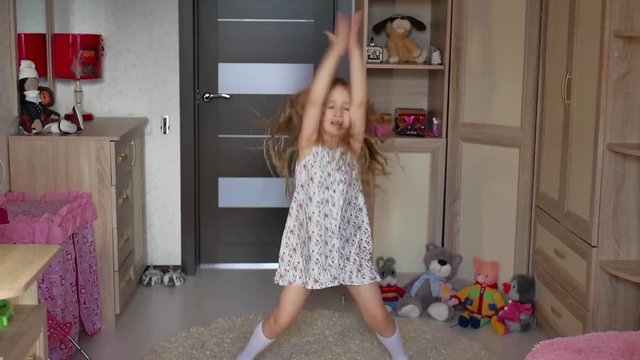 A little girl, adorable young talented dancer does ballet poses and stretching exercises on the floor at home.