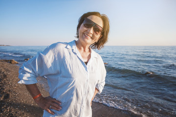 portrait of a stylish attractive mature woman 50-60 years on the seashore, travel and retirement,...