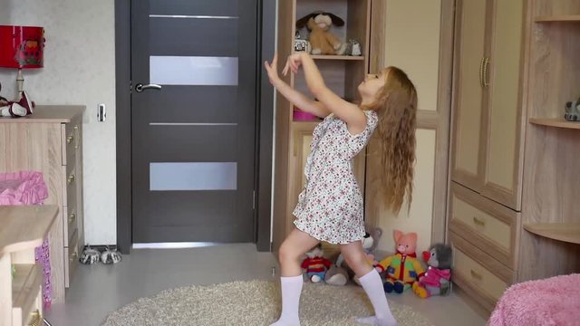 A little girl, adorable young talented dancer does ballet poses and stretching exercises on the floor at home.
