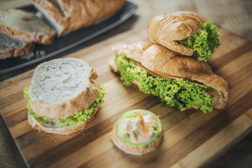 Sandwich with tuna and vegetables on rye bread on wood background