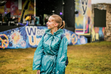 Cute girl in a blue raincoat standing next to the scene