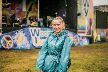 Cute girl in a blue raincoat standing next to the scene