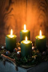 Adventsgesteck mit vier brennenden Kerzen