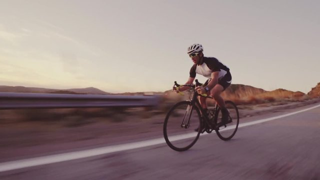 Young Fit Man Cycling On Road Bike Outside At Sunset  Racing Downhill 