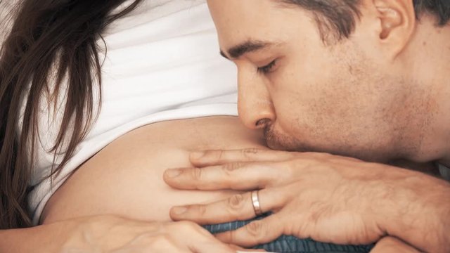 Man kisses his pregnant wife's belly