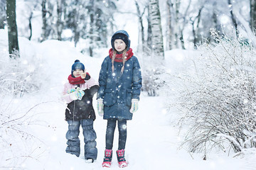 Fototapeta na wymiar two sisters girls winter for a walk / young girlfriends playing in the snow in the frost. The concept of childhood, friendship, family. Sports warm clothes, health immunity. Christmas morning.