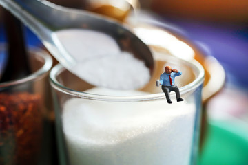 miniature people : fat man sitting on glass of sugar