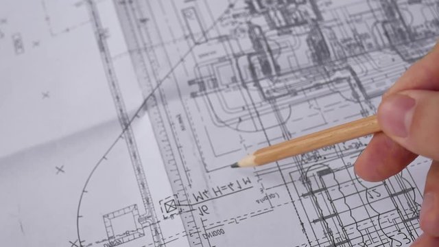 Macro close up of quantity surveyors hand reviewing technical drawing. Architect working on blueprint. Construction concept. Engineering tools. Top view.