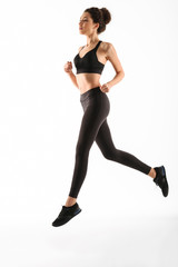 Full length image of Smiling fitness woman running in studio