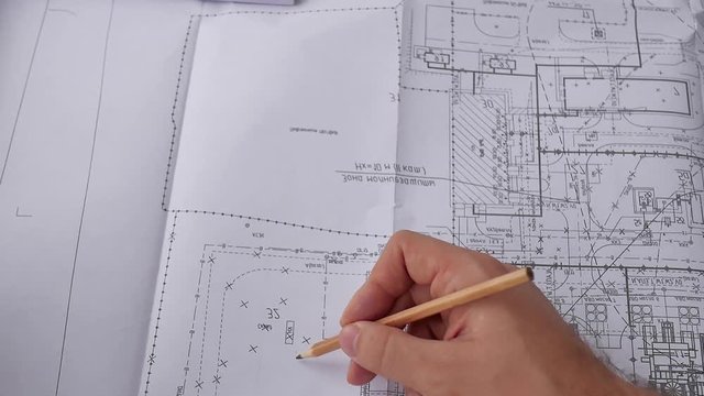 Macro close up of quantity surveyors hand reviewing technical drawing. Architect working on blueprint. Construction concept. Engineering tools. Top view.