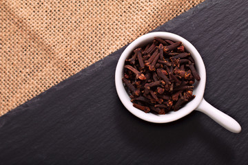 Food concept Spices cloves, on black slate stone and sackcloth background