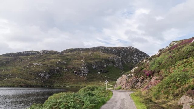 POV shot from a camera attached to the front of a vehicle driving through beautiful empty roads in the scottish highlands