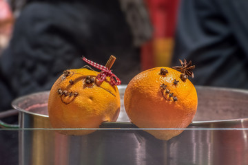Spicy mulled wine with orange in a large cooking pot. Two organs with face decorate the pot at a stall on the Weihnarkt. Selective focus on the oranges. Concept: Christmas or Christmas market