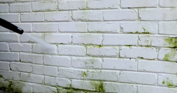 cleaning house brick facade with high pressure washer