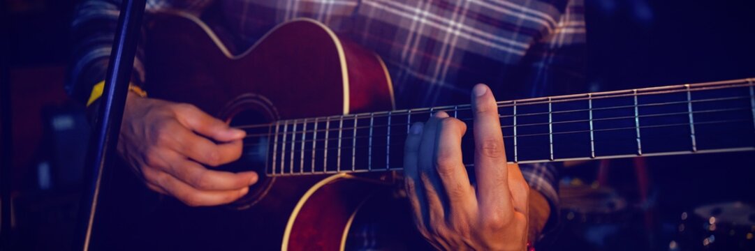 Mid section of guitarist performing on stage