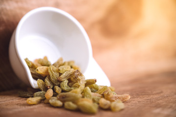 Closeup image of raisin in a white cup on wooden background