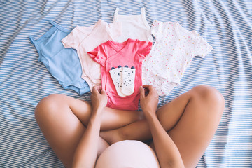Pregnant woman looking of baby clothes.