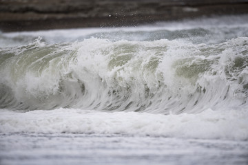 Bei Sturm brechen grosse Wellen an einem strand spülsaum