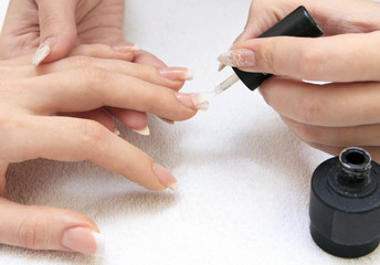 Obraz na płótnie Canvas manicure making - female hands, covering of transparent enamel