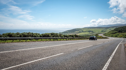 Scottish Highland road trip. A quiet coastal road running through the Highlands of Scotland on a bright summers day. - 184685545