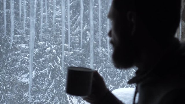 Handsome Man Drinking From A Mug Looking Out Of The Window From Inside House, Wearing A Black Shirt.