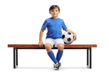 Obraz premium Little footballer sitting on a bench