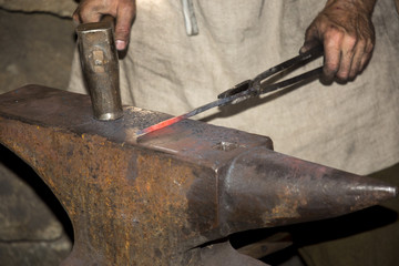 blacksmith while he forges a sword by beating the glowing metal on an anvil