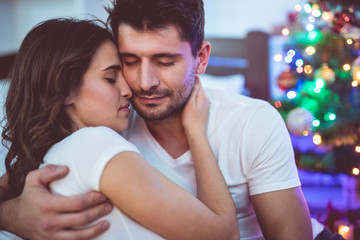 The beautiful couple sit near the christmas tree