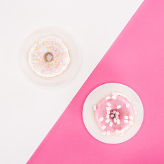 top view of various glazed doughnuts on plated on white and pink surface