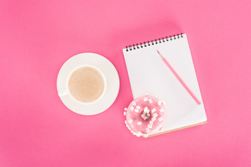 Naklejka premium top view of glazed doughnut with cup of coffee and blank notebook on pink surface
