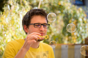 Junger Mann bläst Seifenblasen, draußen