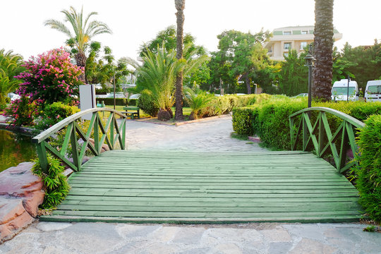 View of beautiful park with wooden bridge and tropical palms at resort