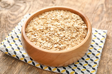 Bowl with oatmeal flakes on wooden background