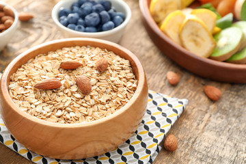 Obraz na płótnie Canvas Bowl with oatmeal flakes and almond on wooden background