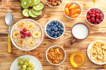 Oatmeal flakes and many different toppings on wooden background