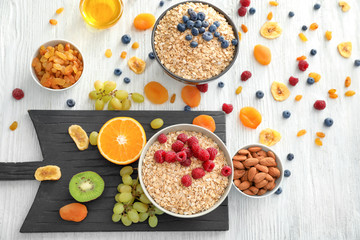 Composition with oatmeal flakes and many different toppings on wooden background