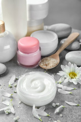 Jar of body cream and flower petals on table