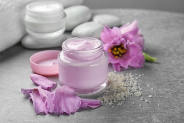 Obraz na płótnie Canvas Jar of body cream and flower petals on table