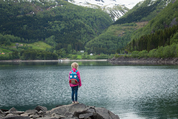 Fototapeta na wymiar little blonde girl at the shore of norwegian lake
