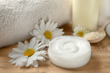 Obraz na płótnie Canvas Jar of body cream and flowers on wooden background