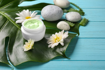 Obraz na płótnie Canvas Jar of body cream and flowers on tropical leaf