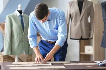 Young tailor working with sewing pattern in atelier