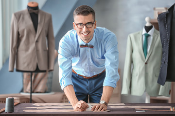 Young tailor working with sewing pattern in atelier