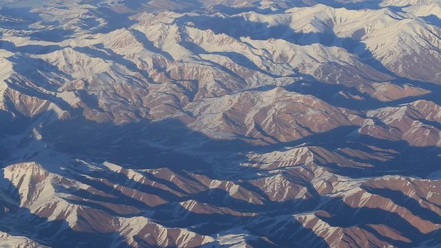 Aerial views in mountain. View from the plane window. The Hindu Kush mountain system in Afghanistan. Top view