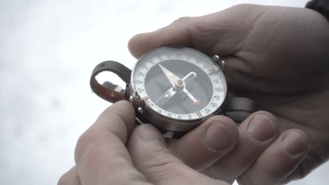 Close up on compass instrument in gloved hand . Mountain hiking trails. Winter mountain trip concept.