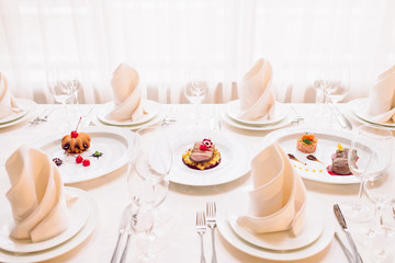 Beautifully served table in a restaurant. Luxury table setting, tableware. Sophisticated, delicious expensive meat dishes served on white plate. Glasses, plates, napkins, forks and knifes