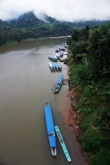 Naklejka premium Blue slow long boats on a river in Laos jungle