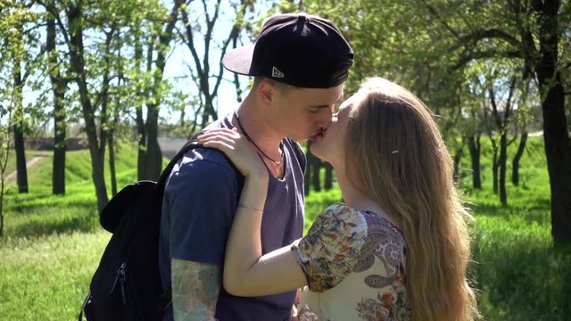 Young Guy and Girl kissing hugging on the green Grass in summer Park